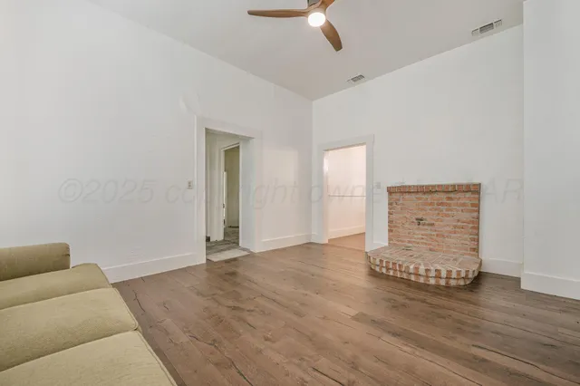an empty room with wooden floor closet and windows