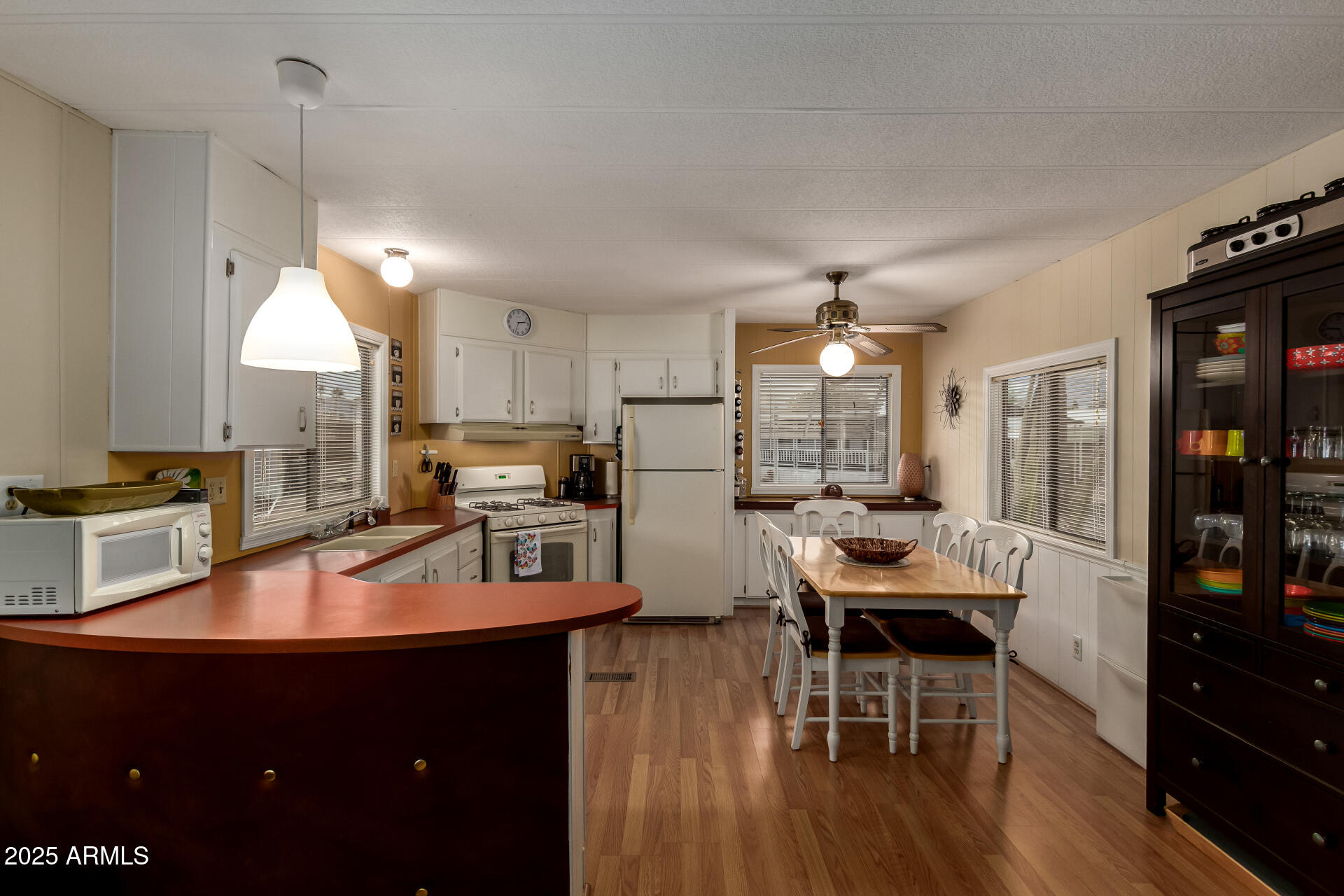 11425 East University Drive, Unit 53 Apache Junction, AZ 85120 - Photo 11 of 29 a kitchen with stainless steel appliances granite countertop a refrigerator a sink dishwasher a dining table and chairs with wooden floor