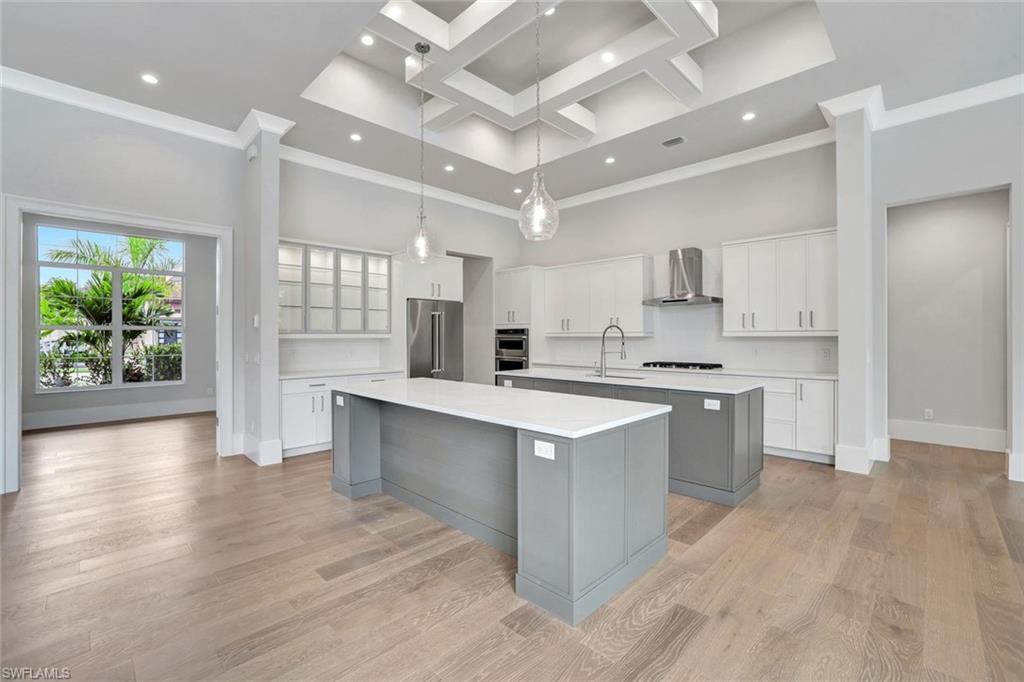 14286 Charthouse Circle Naples, FL 34114 - Photo 10 of 47 Kitchen with gray cabinets, white cabinets, a towering ceiling, coffered ceiling, and hanging light fixtures