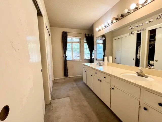 a spacious bathroom with a double vanity sink a large mirror and a bathtub