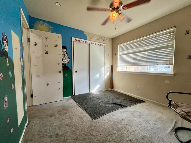 a view of a livingroom with a chandelier fan and windows