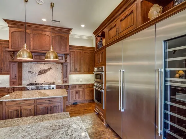 a kitchen with stainless steel appliances granite countertop a refrigerator a sink and a stove