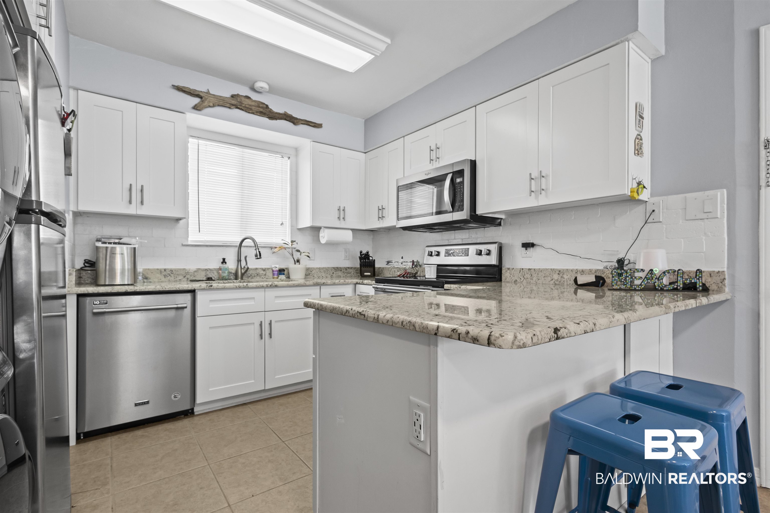 25925 Canal Road, Unit 207 Orange Beach, AL 36561 - Photo 20 of 42 Kitchen featuring light stone counters, appliances with stainless steel finishes, white cabinetry, and light tile floors
