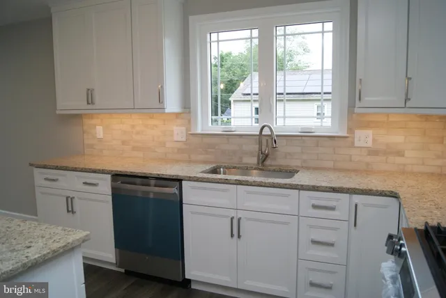 a kitchen with granite countertop white cabinets and a sink
