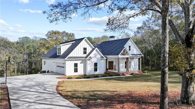 a view of a white house next to a yard with large trees