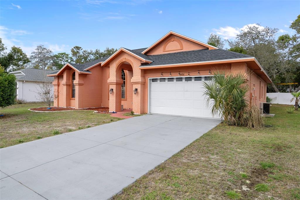 4401 Plumosa Street Spring Hill, FL 34607 - Photo 2 of 38 a front view of a house with a yard and garage