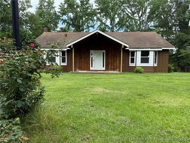 a front view of a house with a yard and trees