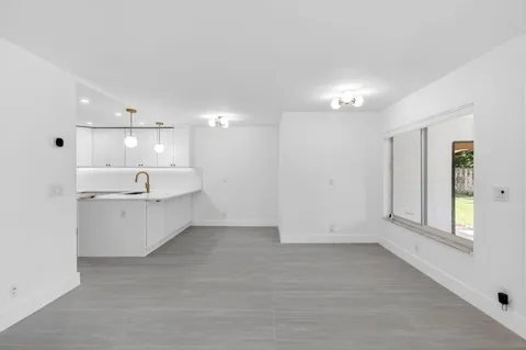 a large white kitchen with white cabinets and wooden floors