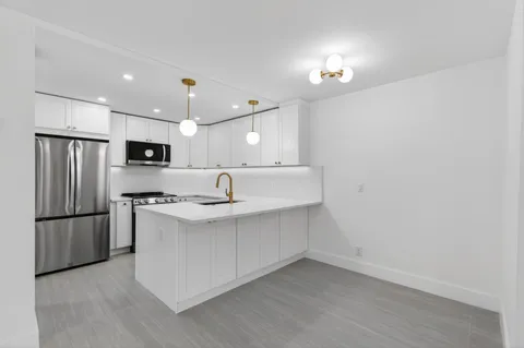 a kitchen with stainless steel appliances granite countertop a refrigerator a sink dishwasher a stove with white cabinets and wooden floor