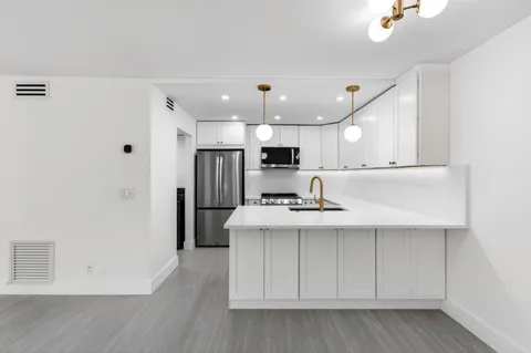 a view of kitchen with stainless steel appliances refrigerator stove microwave and cabinets