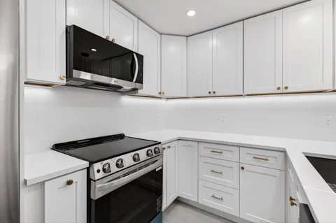 a kitchen with white cabinets and black appliances