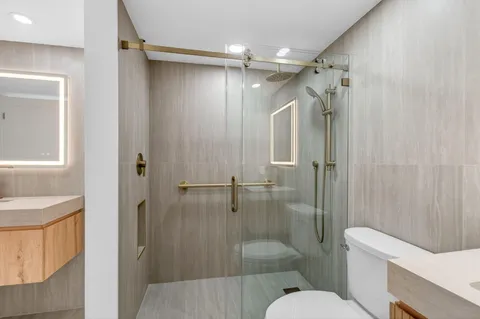 a bathroom with a shower sink vanity mirror and toilet