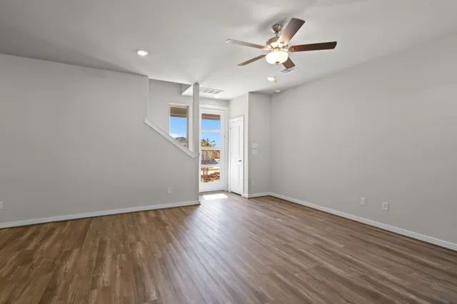 an empty room with wooden floor and ceiling fan