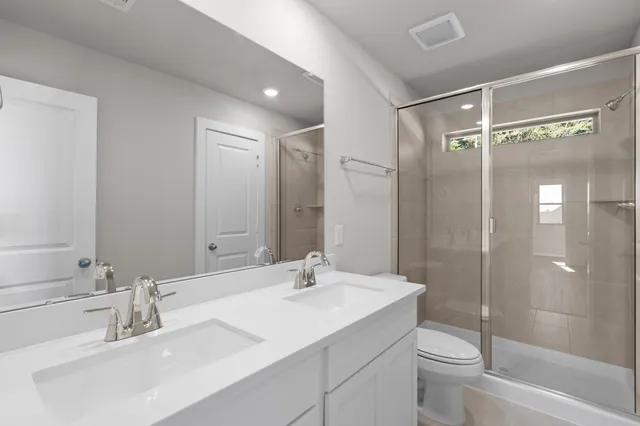 a bathroom with a shower sink vanity mirror and toilet