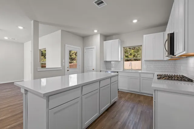a large white kitchen with wooden floors and stainless steel appliances