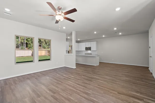 a view of an empty room with window and wooden floor