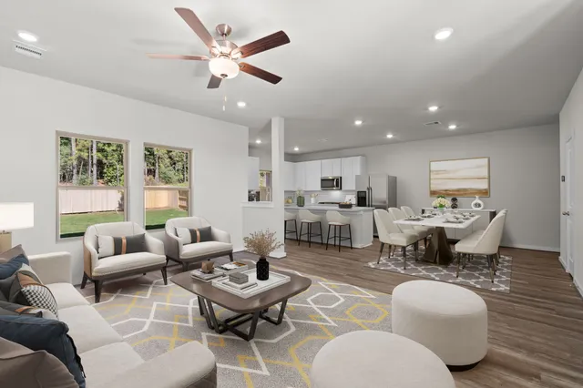a living room with furniture kitchen view and a large window