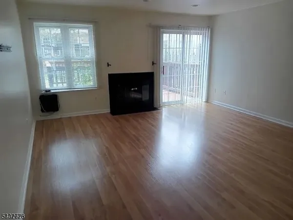 an empty room with wooden floor fireplace and windows