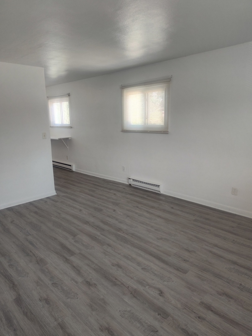 1039 Sheridan Road, Unit 3 Winthrop Harbor, IL 60096 - Photo 2 of 9 a view of an empty room with wooden floor and a window