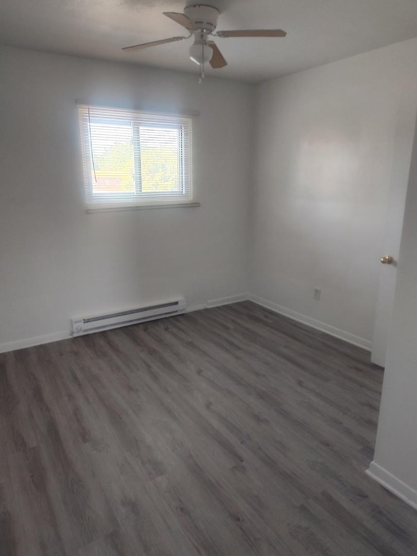 1039 Sheridan Road, Unit 3 Winthrop Harbor, IL 60096 - Photo 6 of 9 an empty room with wooden floor and windows