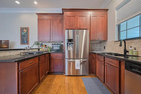 a kitchen with granite countertop wooden floors stainless steel appliances a sink