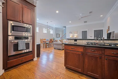 a kitchen with stainless steel appliances granite countertop wooden cabinets a refrigerator a stove a sink and dishwasher with wooden floor