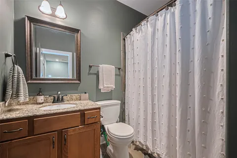 a bathroom with a granite countertop toilet sink and mirror