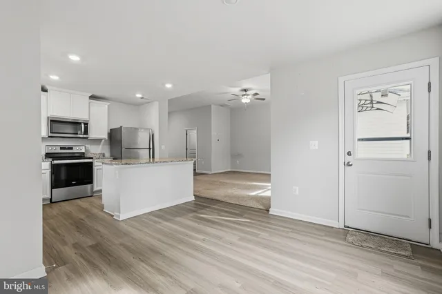 a view of kitchen with stainless steel appliances kitchen island granite countertop a refrigerator and a stove top oven