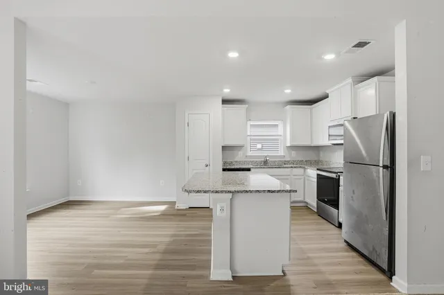 a kitchen with stainless steel appliances granite countertop a refrigerator a stove and a sink