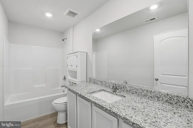 a bathroom with a granite countertop sink a toilet and shower