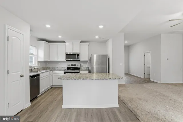 a large kitchen with stainless steel appliances granite countertop a stove a sink a refrigerator and a granite counter tops with wooden floors