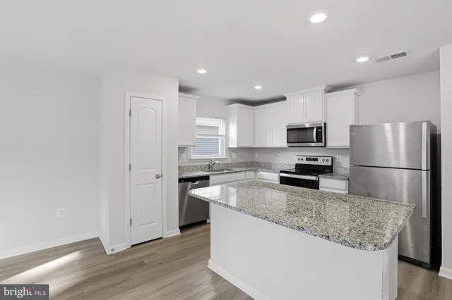 a kitchen with a sink a refrigerator a microwave and cabinets