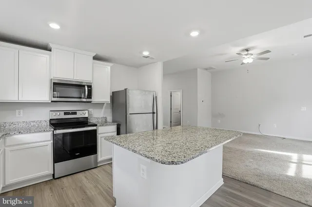 a kitchen with kitchen island a sink stainless steel appliances and cabinets