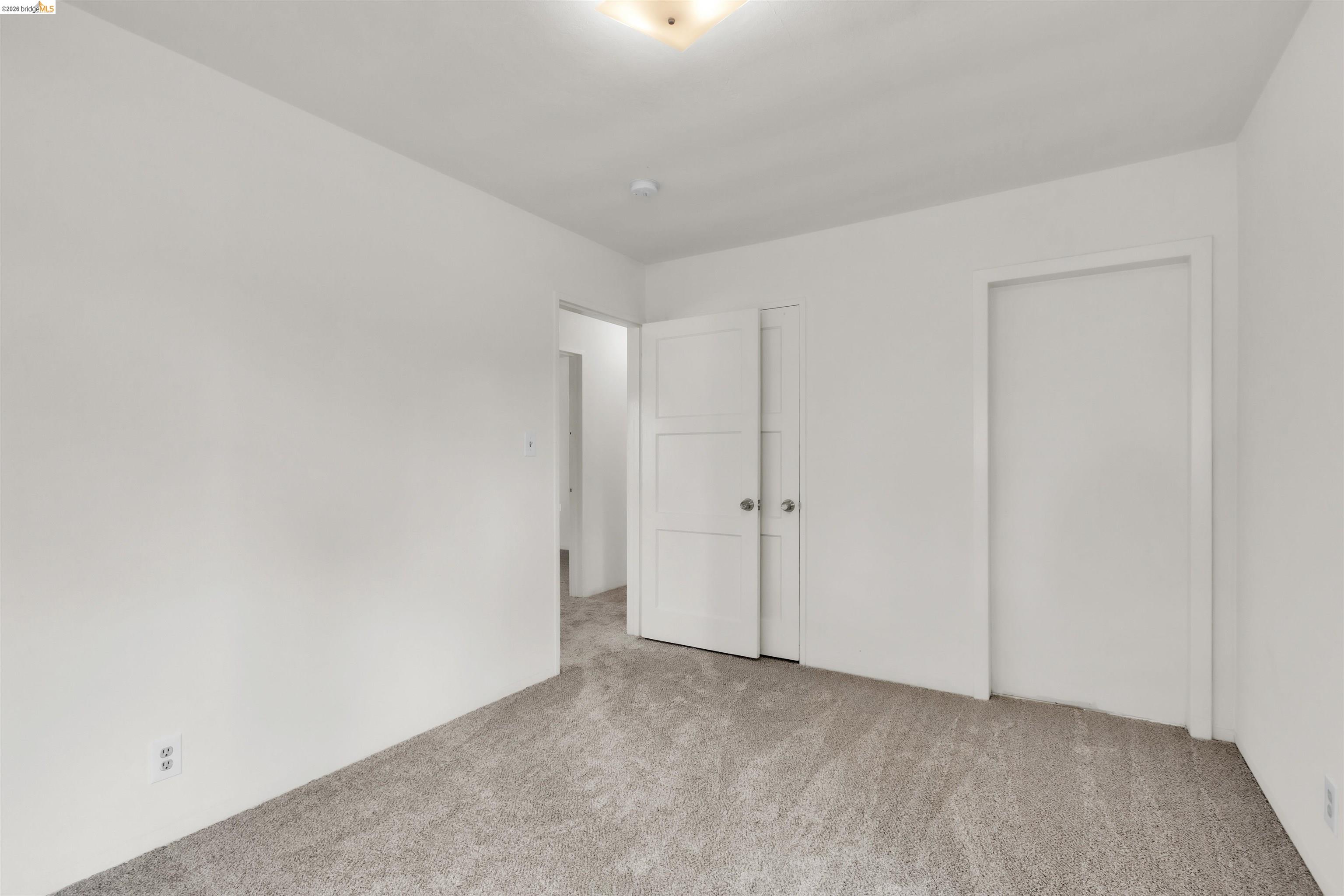 621 Paseo Del Rio San Lorenzo, CA 94580 - Photo 20 of 24 Carpeted room with white walls, featuring a ceiling-mounted light fixture, and two panel doors