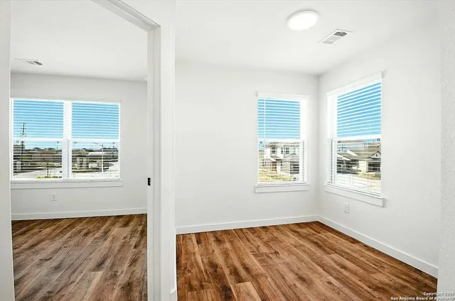 a view of an empty room with wooden floor and a window