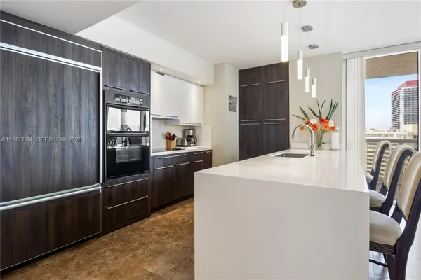 a kitchen with stainless steel appliances kitchen island granite countertop a refrigerator a stove and a sink with wooden floor