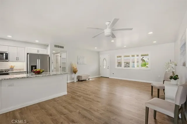 a view of an empty room and kitchen with wooden floor