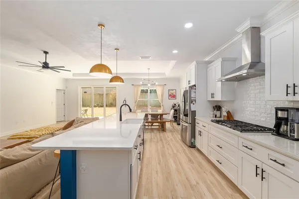 a large white kitchen with a stove a sink a refrigerator and a wooden floor