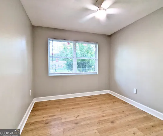 a view of empty room with wooden floor and fan