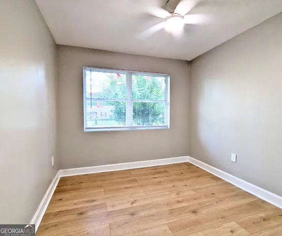 a view of empty room with wooden floor and fan