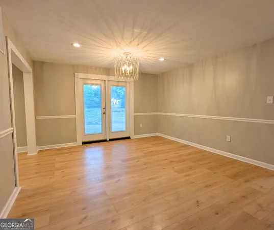 an empty room with wooden floor and natural light