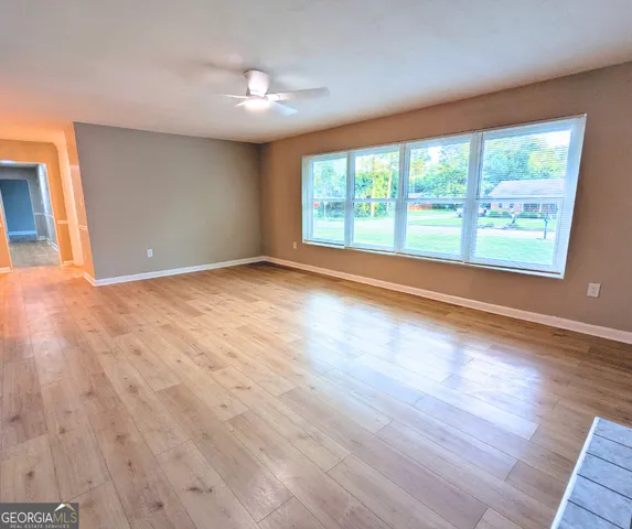 a view of an empty room with wooden floor and a window