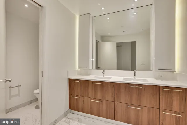 a bathroom with a double vanity sink a mirror and a toilet