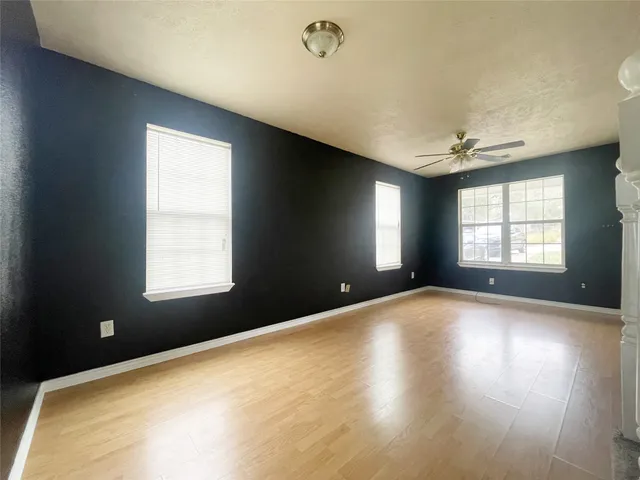 a view of an empty room with a window and wooden floor