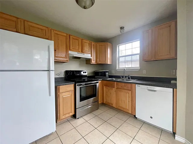 a kitchen with granite countertop a refrigerator and a sink