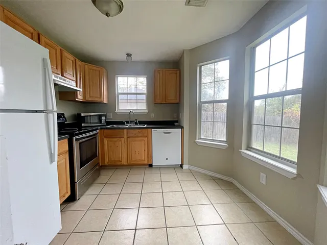 a kitchen with a stove a sink dishwasher and a refrigerator