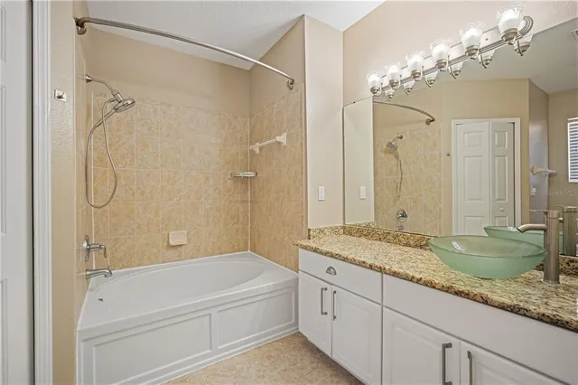 a bathroom with a granite countertop sink a mirror a bathtub and shower