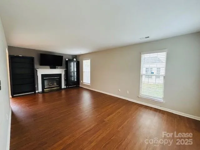 an empty room with wooden floor fireplace and windows