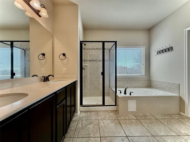 a spacious bathroom with a tub sink shower and mirror