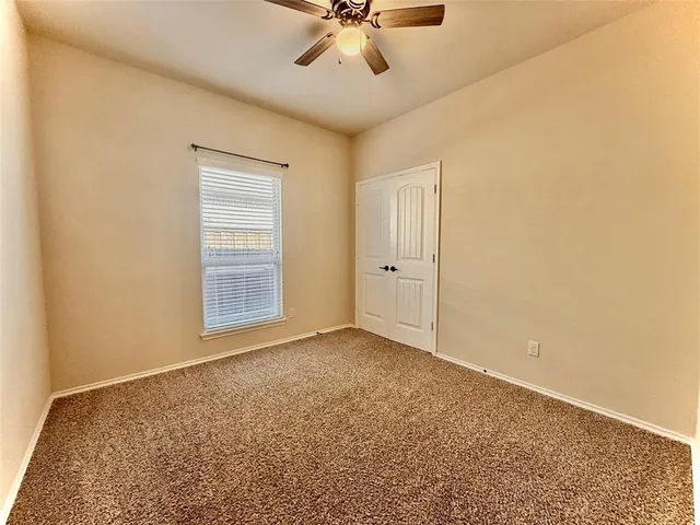 an empty room with a ceiling fan and a window
